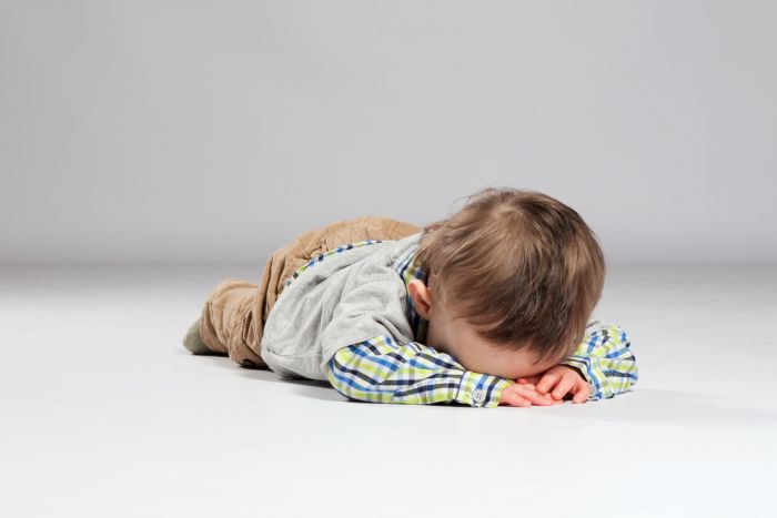 ילד קטן נשכב על הרצפה לאחר שאמרו לו לא